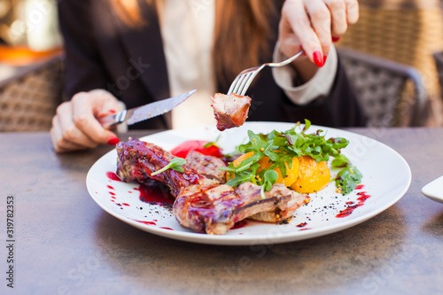 Woman eat healthy lunch in restaurant. Grilled meat steak with cranberry sauce, glazed peaches and arugula salad photo