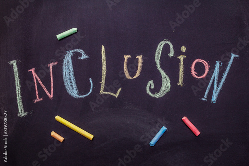 Word Inclusion on black school blackboard written with chalk. Education concept