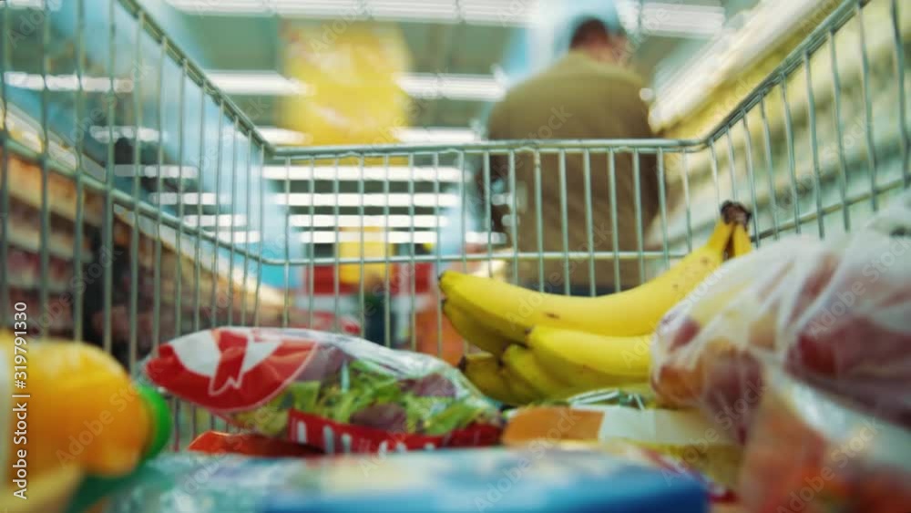 Time-lapse inside shopping trolley with healthy fresh food fruits vegetables moving through supermarket sections and aisles with stuff. Grocery shopping concept. Close-up.