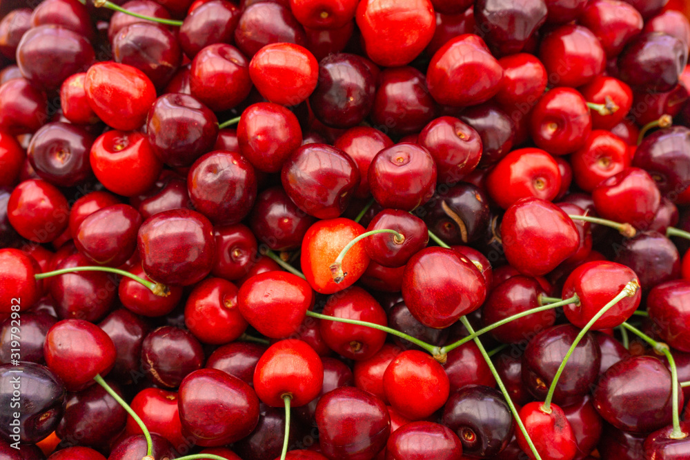 Pile of ripe cherries with stalks and leaves. Large collection of fresh red cherries. Ripe cherries background. Pile of ripe cherries with stalks and leaves. Large collection of fresh red cherries. Ripe cherries background.