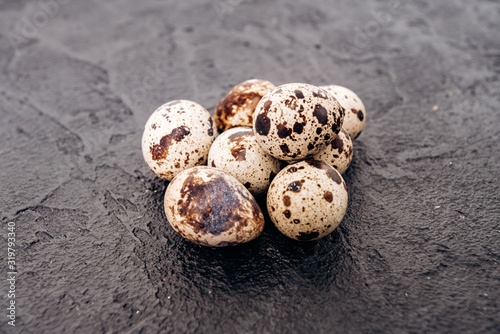 Quail eggs on a black background. Several quail eggs lie on a black stone background