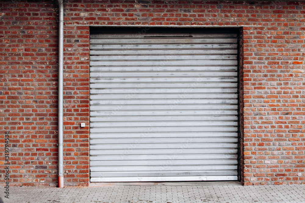Large garage door with brick wall and asphalt driveway Large garage door with brick wall and asphalt driveway