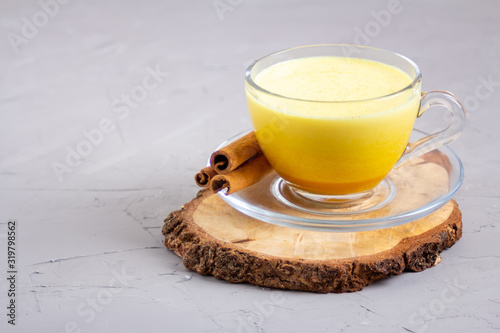 Golden milk in a glass gray cup on a gray background