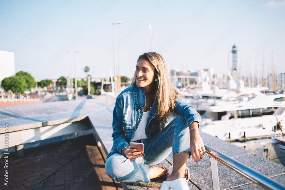 Fototapeta premium Cheerful lady using video call on smartphone relaxing at waterside