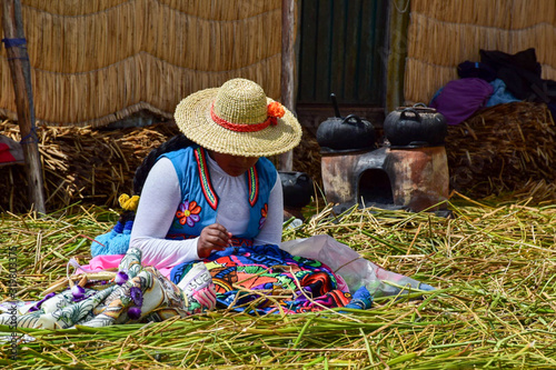 A women sewing artisanal clothes on a flooding island on lake titicaca in Peru