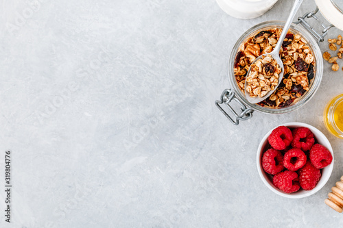 Healthy breakfast Granola with fresh raspberry and honey on gray stone background