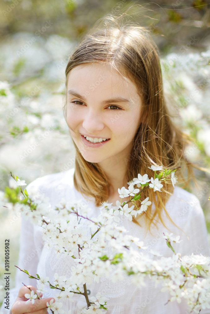 Adorable little girl in blooming apple tree garden on beautiful spring day.