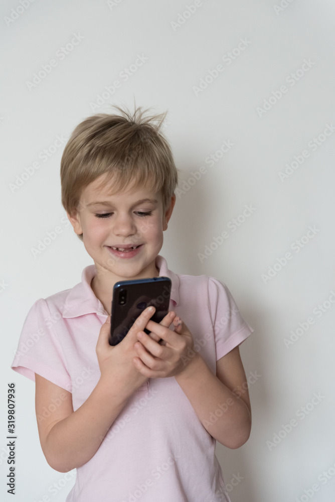 A cute child is laughing loudly, holding a cell phone in his hand. A cute child is laughing loudly, holding a cell phone in his hand.