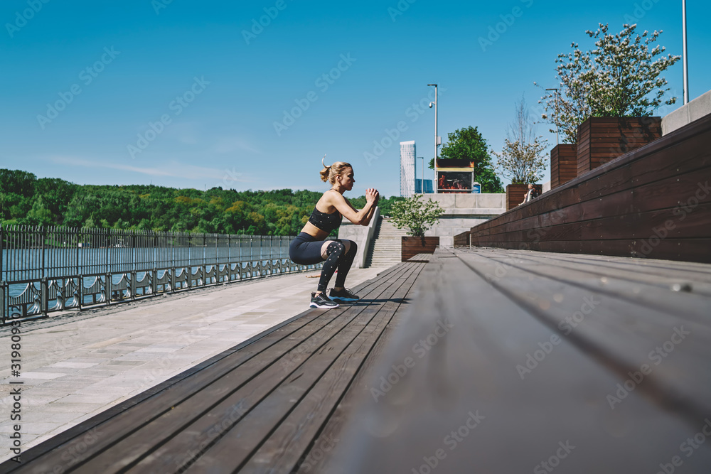 Focused lady doing squatting at promenade