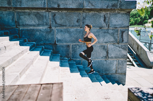 Fit woman in active wear training stamina while running upstairs at outdoors stadium