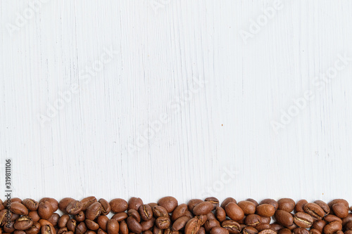 Roasted coffee beans on a white wooden background. Copy space. © gesrey