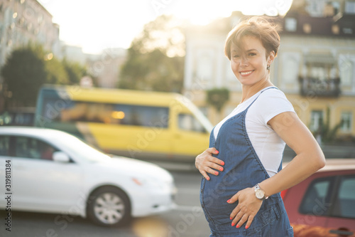 Pregnant Woman Walks Outdoors Through Urban Street In Sunny Day