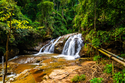 Beautiful waterfall Mae Sa  Thailand. Fresh and pure water stream is flowing on the rock stone ground in tropical rainforest. Fresh plants and trees above river. Vibrant colors in pure nature