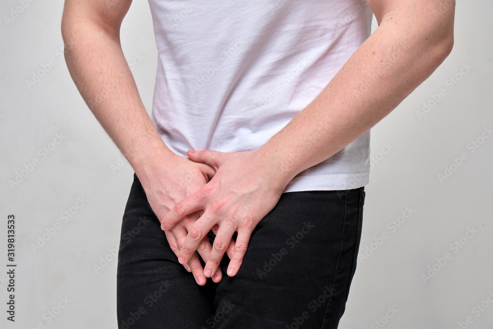 A man in a white T-shirt suffers groin pain. The problem with urology. A man in a white T-shirt suffers groin pain. The problem with urology.