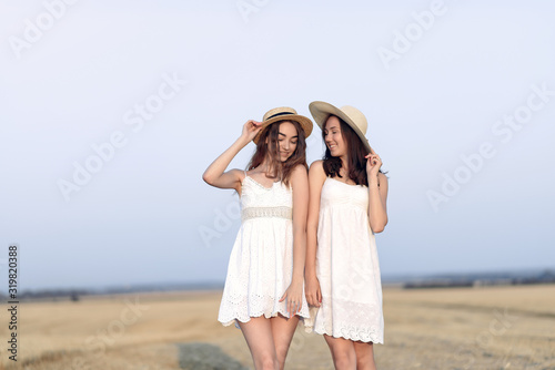 Beautiful girls in a white dress. Women in a autumn field. Brunette in a brown hat