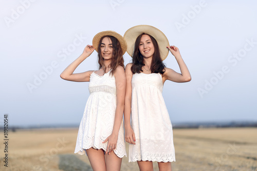 Beautiful girls in a white dress. Women in a autumn field. Brunette in a brown hat