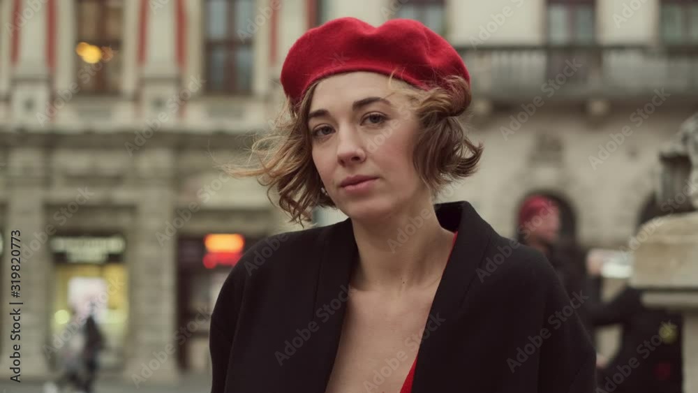 Portrait Of Stylish Young Woman On City Street. Woman Is Serious At First And Then Smiles. Portrait Of Stylish Young Woman On City Street. Woman Is Serious At First And Then Smiles.