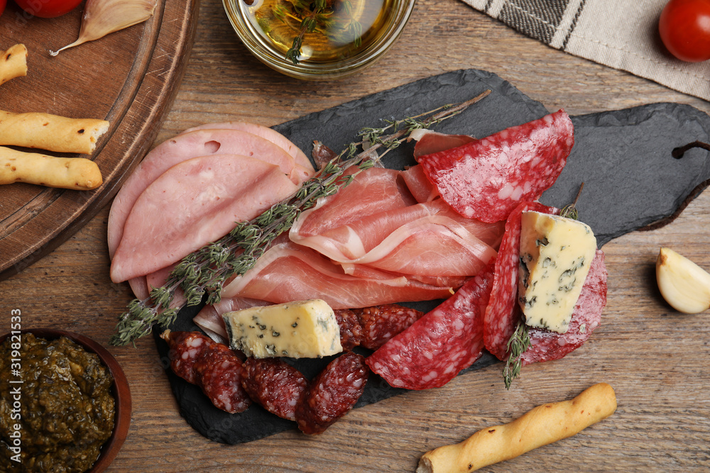 Tasty ham with other delicacies served on wooden table, flat lay