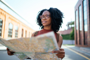 Young student walking outside university while exploring places with help of map