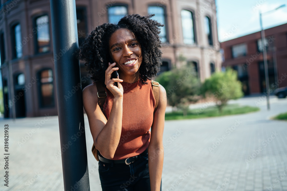 Relaxed African American student chatting on smartphone