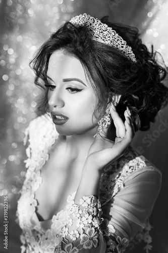 Black and white photo. Beautiful happy bride in white silk robe in her bedroom in a morning. Beauty woman with wedding hairstyle and makeup. Bride fashion. Jewelry and Beauty. 
