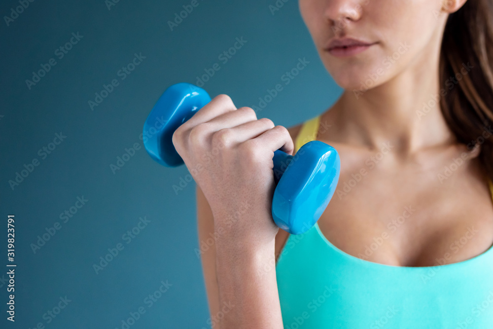 Sporty young woman doing muscular exercise with dumbbells on gym. Sporty young woman doing muscular exercise with dumbbells on gym.