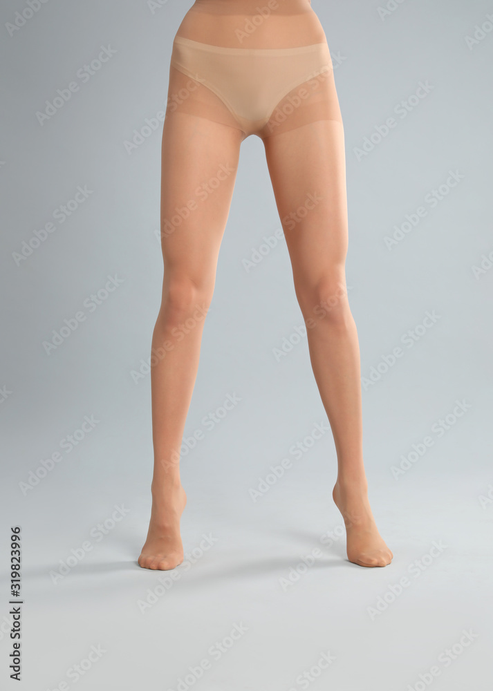 Woman wearing tights on light grey background, closeup of legs Woman wearing tights on light grey background, closeup of legs