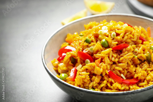 Delicious rice pilaf with vegetables in bowl on table, closeup