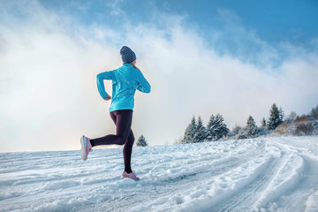 Running woman. Runner on the snow in winter sunny day. Female fi