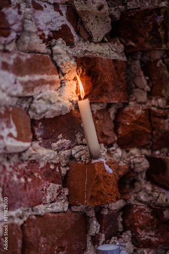 white wax candle burns on a brick background
