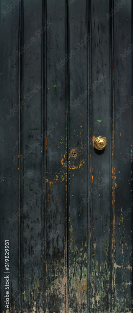 Fototapeta premium old wooden door with golden knob and vertical panels - rough texture with scratches and dark blue texture
