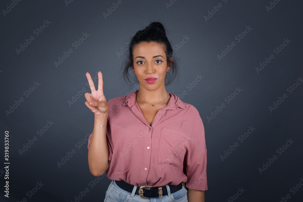 Young middle aged caucasian woman standing against gray wall showing and pointing up with fingers number two while smiling confident and happy. Young middle aged caucasian woman standing against gray wall showing and pointing up with fingers number two while smiling confident and happy.