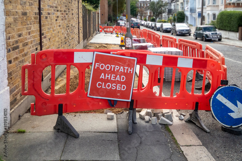 Works to lay new paving slabs and temporary footpath closed red warning sign on London sidewalk