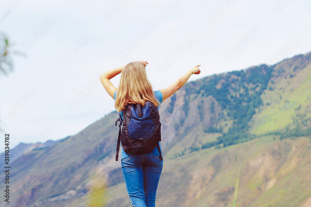 the girl stands with her back against the mountains