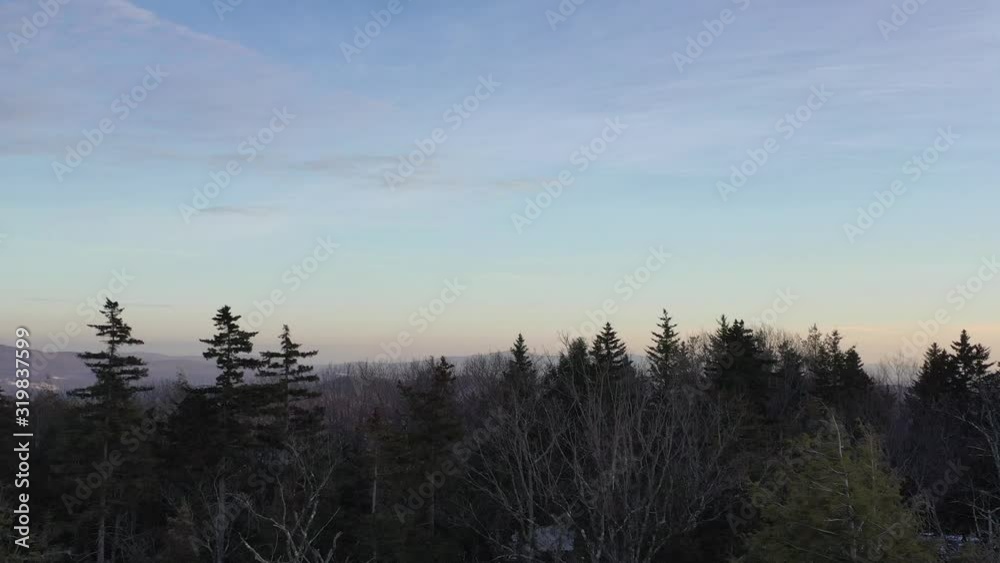Aerial 4K drone shot of rural winter landscape revealed over pine trees on mountain ridge. Aerial 4K drone shot of rural winter landscape revealed over pine trees on mountain ridge.
