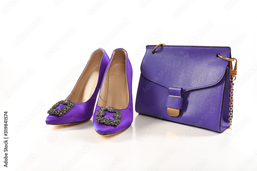 Violet patent leather shoes and small handbag on a white background