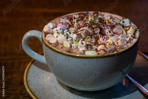 Cacao mug with marshmallows and cinnamon on a brown wooden table.