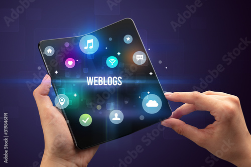 Businessman holding a foldable smartphone with WEBLOGS inscription, social media concept