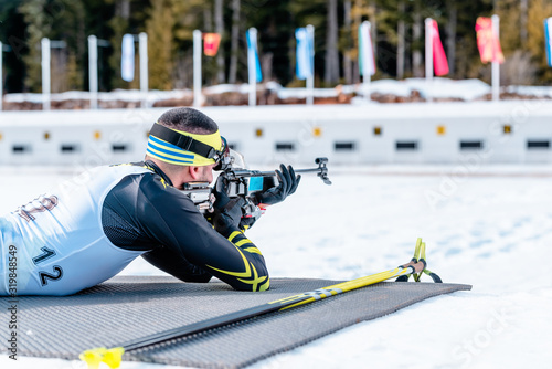 Biathlete shooting with a rifle at a shooting range at the race photo