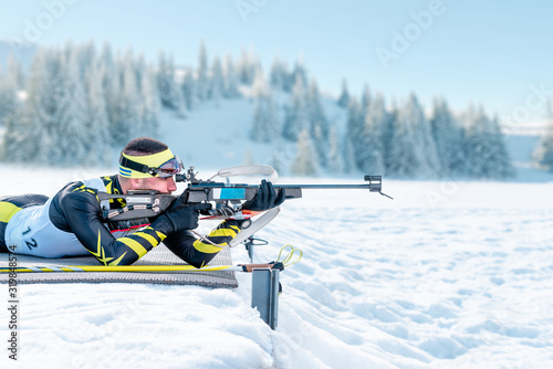 Biathlete shoots in the prone position on training ground photo