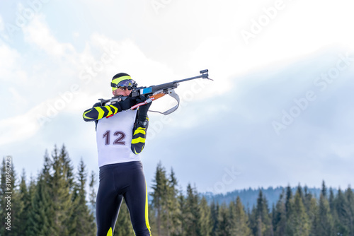 Biathlete holds his breath while shooting the rifle in a standing position during the biathlon race photo