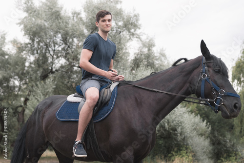 man riding on a dark horse in forest