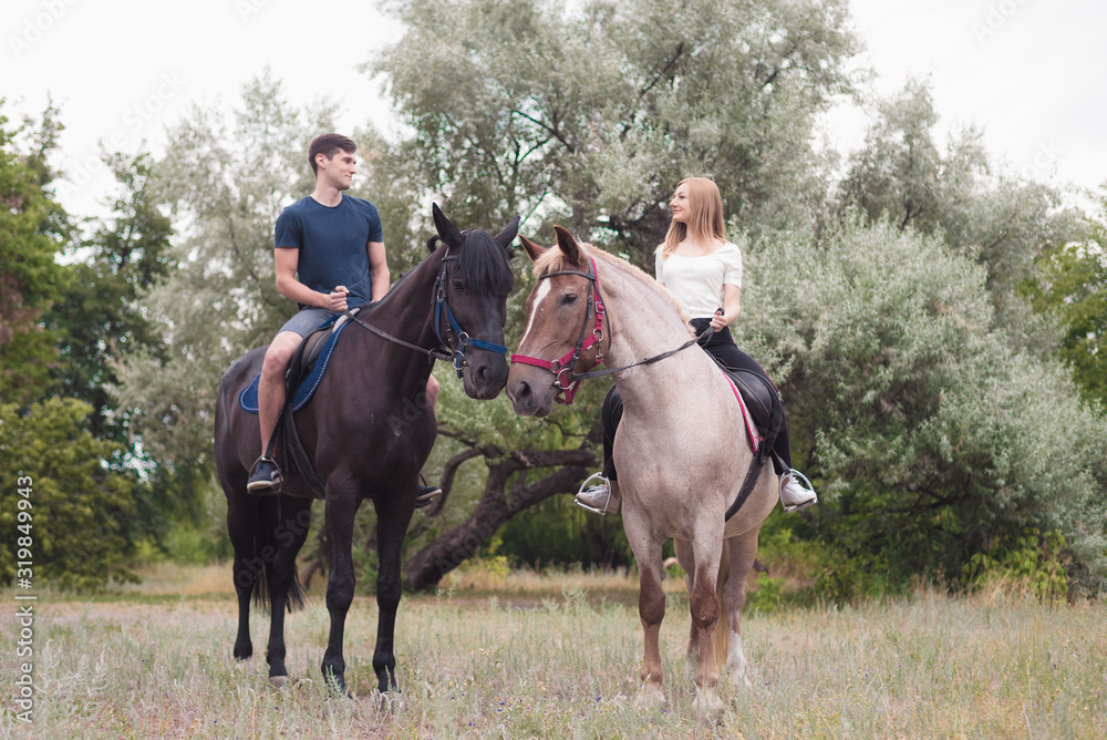 beautiful couple sitting on a horses in forest