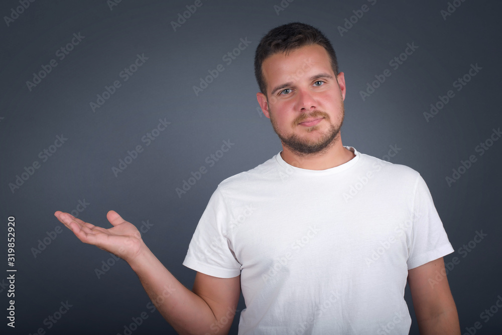 Positive glad male says: wow how exciting it is, has amazed expression, shows something on blank space with open hand over isolated gray background. Advertisement concept. Positive glad male says: wow how exciting it is, has amazed expression, shows something on blank space with open hand over isolated gray background. Advertisement concept.