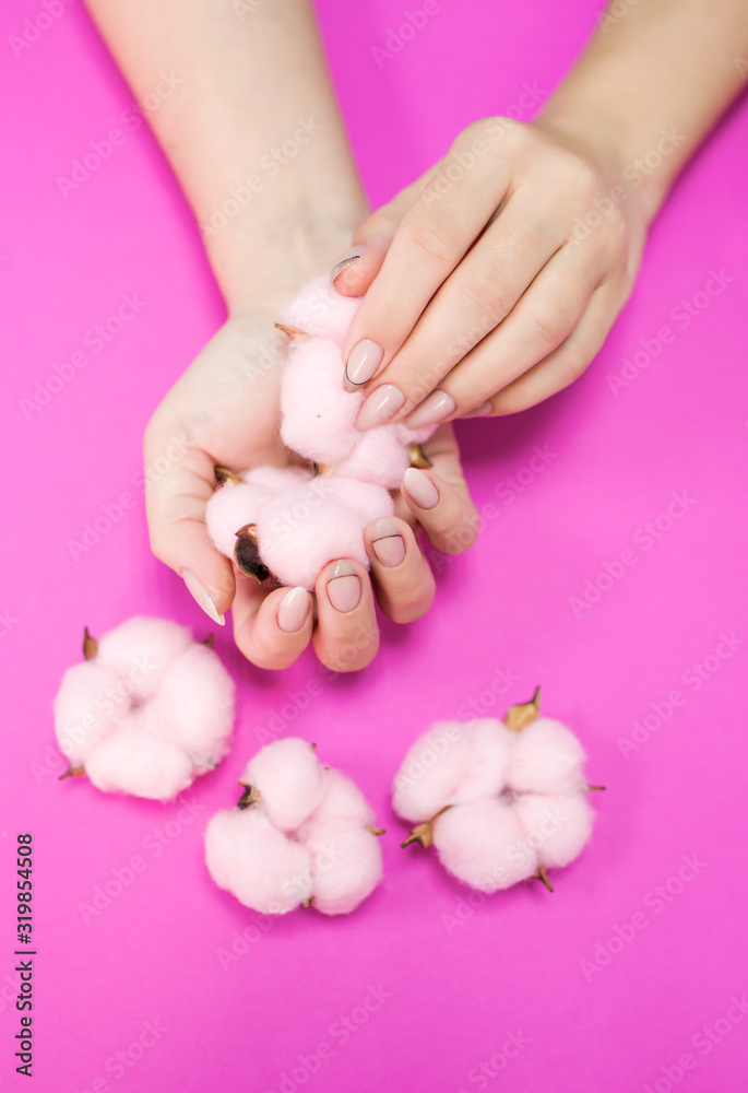 Beautiful women's manicure in delicate tones, on a bright background with gently pink cotton. Place for the inscription.