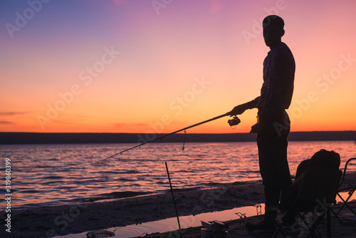 fisherman silhouette with pink sky and river