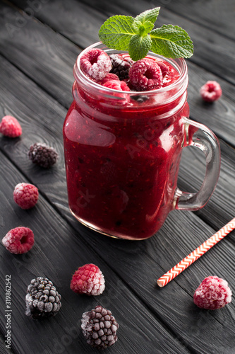 Fototapeta Naklejka Na Ścianę i Meble -  Smoothies with frozen blackberry and raspberries on the  black wooden background. Location vertical. Closeup.
