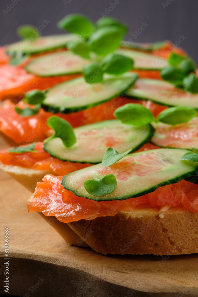 Sandwich with salmon on wooden plate
