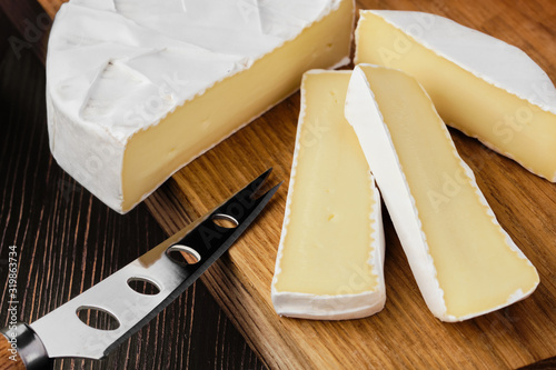 Fotografija Close up of camembert or brie cheese on wooden cutting board (macro photo with s