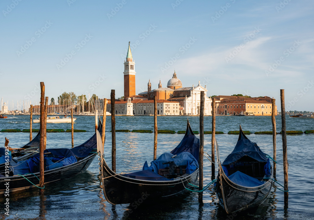 Row of gondolas moored beside the Riva degli Schiavoni against boats and San Giorgio Maggiore island, Venice, Italy